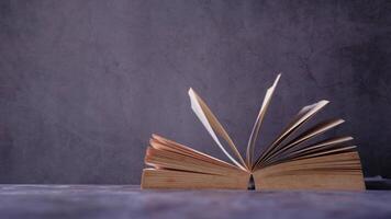 An open book on a table with a dark background video