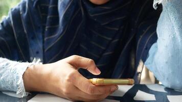 A woman in a blue scarf holding a cell phone video