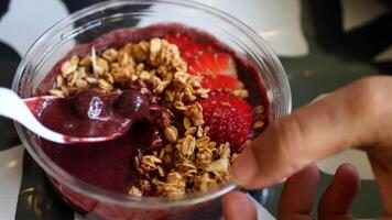 A person holding a spoon over a bowl of fruit video