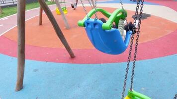 child having fun on a swing on the playground in public park. video