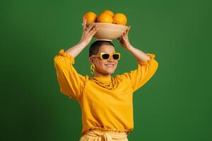 Happy young short hair woman carrying plate with oranges on head against green background photo