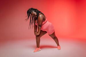 Happy plus size woman in sportswear exercising and looking confident on colorful background photo