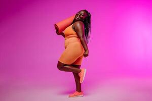 Active young voluptuous woman in sportswear carrying exercise mat and smiling on pink background photo