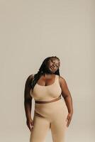 Confident African plus size woman in underwear radiating self-love while standing on studio background photo
