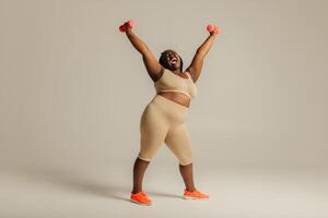 Confident plus size African woman in sportswear radiating confidence while exercising on studio background photo