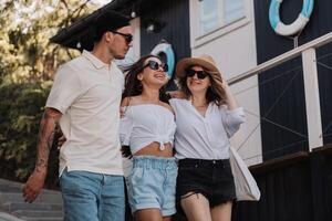 Three happy young friends walking and smiling while spending summer day together photo