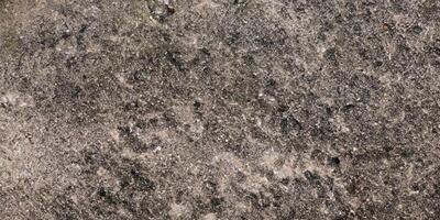 Close-up texture of rough weathered concrete surface with dark patches photo