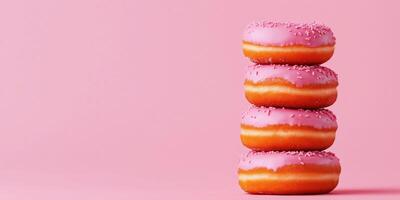 Stack of pink frosted donuts with sprinkles on a soft pink background photo