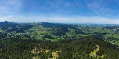 Aerial panoramic view of lush green landscape with expansive forests and rolling hills photo