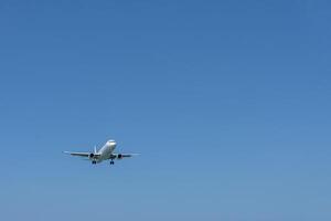 An approaching plane in the empty blue sky. A large expanse of empty sky. photo