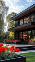Modern black wooden house with large terrace and garden in bloom photo