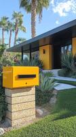 Yellow mailbox standing in front of a modern house with palm trees photo