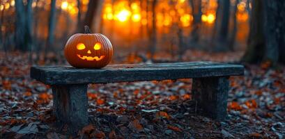 A pumpkin with a smiley face on it sits on a bench in a forest. The scene is set during the fall season, with leaves scattered around the bench. Halloween photo