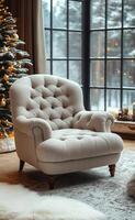 A white chair with a fluffy texture sits in front of a Christmas tree. The chair is positioned near a window, which lets in natural light and a view of the snowy landscape outside photo