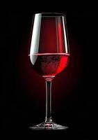 A glass of red wine is shown in a black background. The wine is almost empty, with only a small amount of liquid left in the glass. Concept of relaxation and enjoyment photo