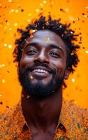 A man with a beard and a smile is standing in front of a yellow background. He is surrounded by confetti, which adds a festive and celebratory atmosphere to the image photo