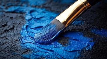 A blue paint brush is being used to paint a blue color on a black surface photo