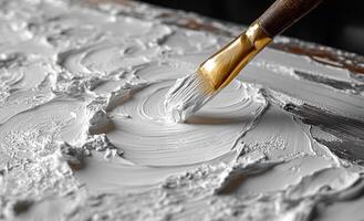 A brush is being used to paint a white surface. The brush is being used to create a texture on the surface, which gives the painting a unique and interesting appearance photo