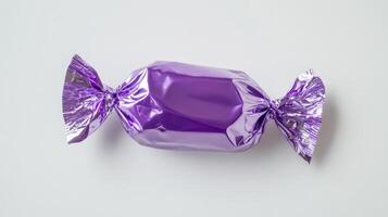 A shiny purple candy, wrapped in vibrant foil, stands out against a clean background. This image is ideal for showcasing sweet treats and designing appealing confectionery products photo