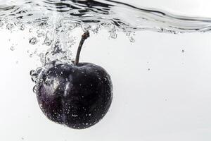 A black plum is floating in water with a splash photo