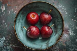 Four red plums in a bowl on a table photo