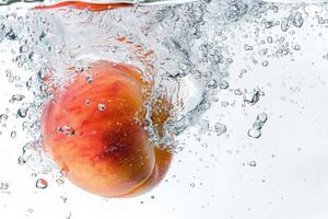 A peach is being dropped into water photo