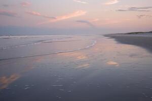 Pastel reflections on calm beach waves at twilight photo