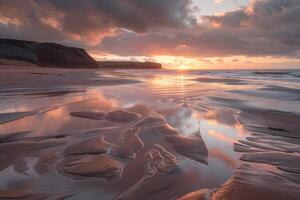 Sunset reflections on sandy beach with tide pools and cliffs photo
