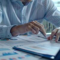 Close-up of a business professional analyzing financial data and charts, working with documents and graphs at a desk. photo