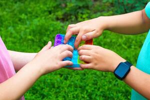 Child's hands are played square multicolored bubble toy antistress sensory pop it. photo
