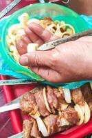 a man's hand stringing gray meat on a skewer to fry a kebab. photo