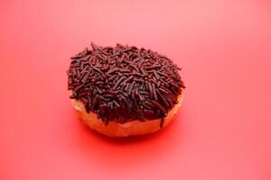 donut with chocolate sprinkle isolated on red background photo