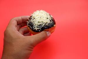 hand holding donut cake isolated on red background. photo