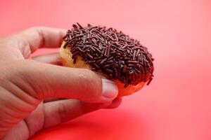 hand holding donut cake isolated on red background. photo