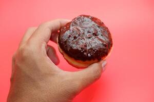 hand holding donut cake isolated on red background. photo