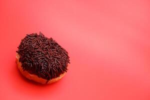 donut with chocolate sprinkle isolated on red background photo