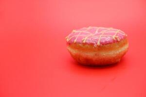 donut cake with pink chocolate glaze and white chocolate smeared in zigzag. donut cake isolated on red background. photo