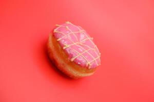 donut cake with pink chocolate glaze and white chocolate smeared in zigzag. donut cake isolated on red background. photo