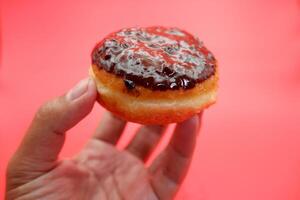 hand holding donut cake isolated on red background. photo