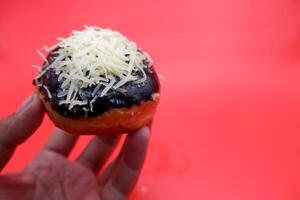 hand holding donut cake isolated on red background. photo