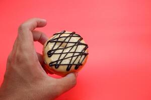 hand holding a donut cake isolated on red background. photo