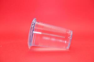 mineral water in plastic cup. mineral water isolated on red background. photo