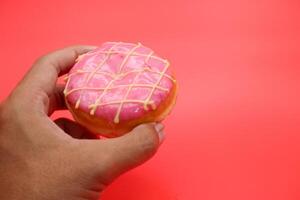 hand holding donut cake isolated on red background. photo