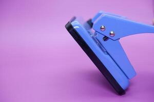 Blue paper punch isolated on purple background photo