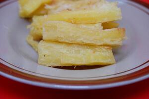 Fried cassava served on a plate. Fried cassava dish isolated on a red background. photo