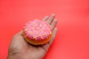 hand holding donut cake isolated on red background. photo