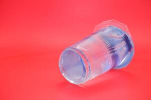 mineral water in plastic cup. mineral water isolated on red background. photo