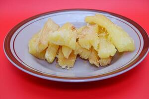 Fried cassava served on a plate. Fried cassava dish isolated on a red background. photo