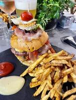 Tasty homemade burger with fries accompanied by ketchup and mayonnaise sauces photo