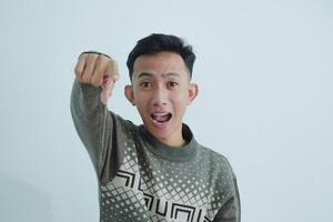 Asian young man showing pointing gesture with gesture and expression. Isolated on white background photo